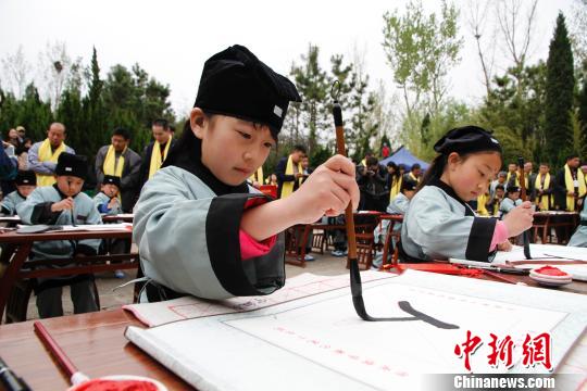 孔子故里的学童们在夫子洞广场参加戊戌年学童启蒙开笔礼，学写“人”字。(资料图) 沙见龙 摄